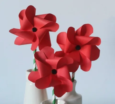 Red poppies made out of paper in a pinwheel shape.