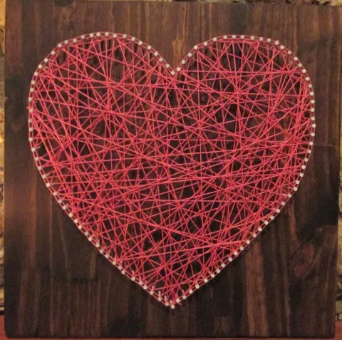 A heart made out of red string wound around nails.