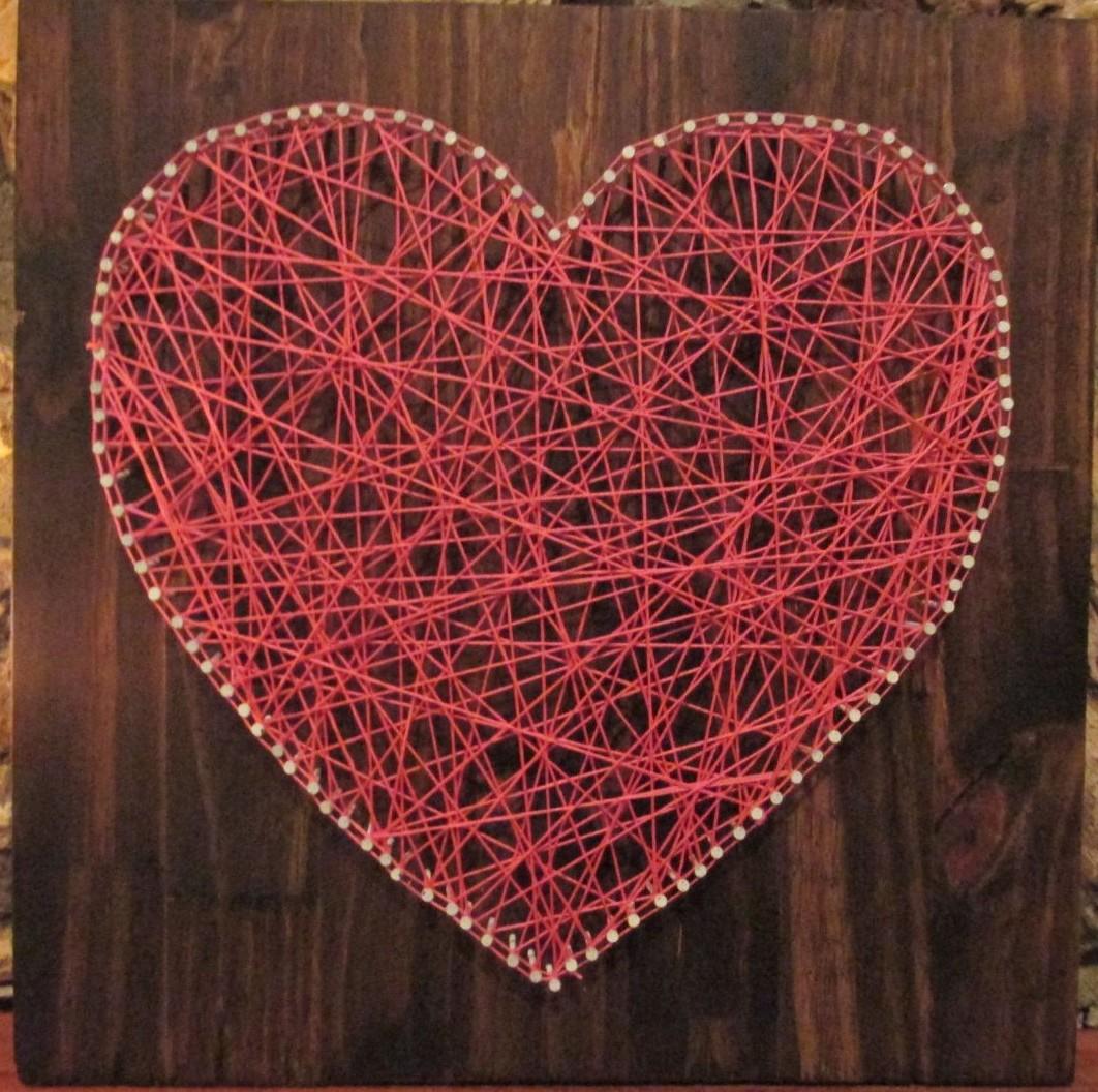 A heart made out of red string wound around nails.